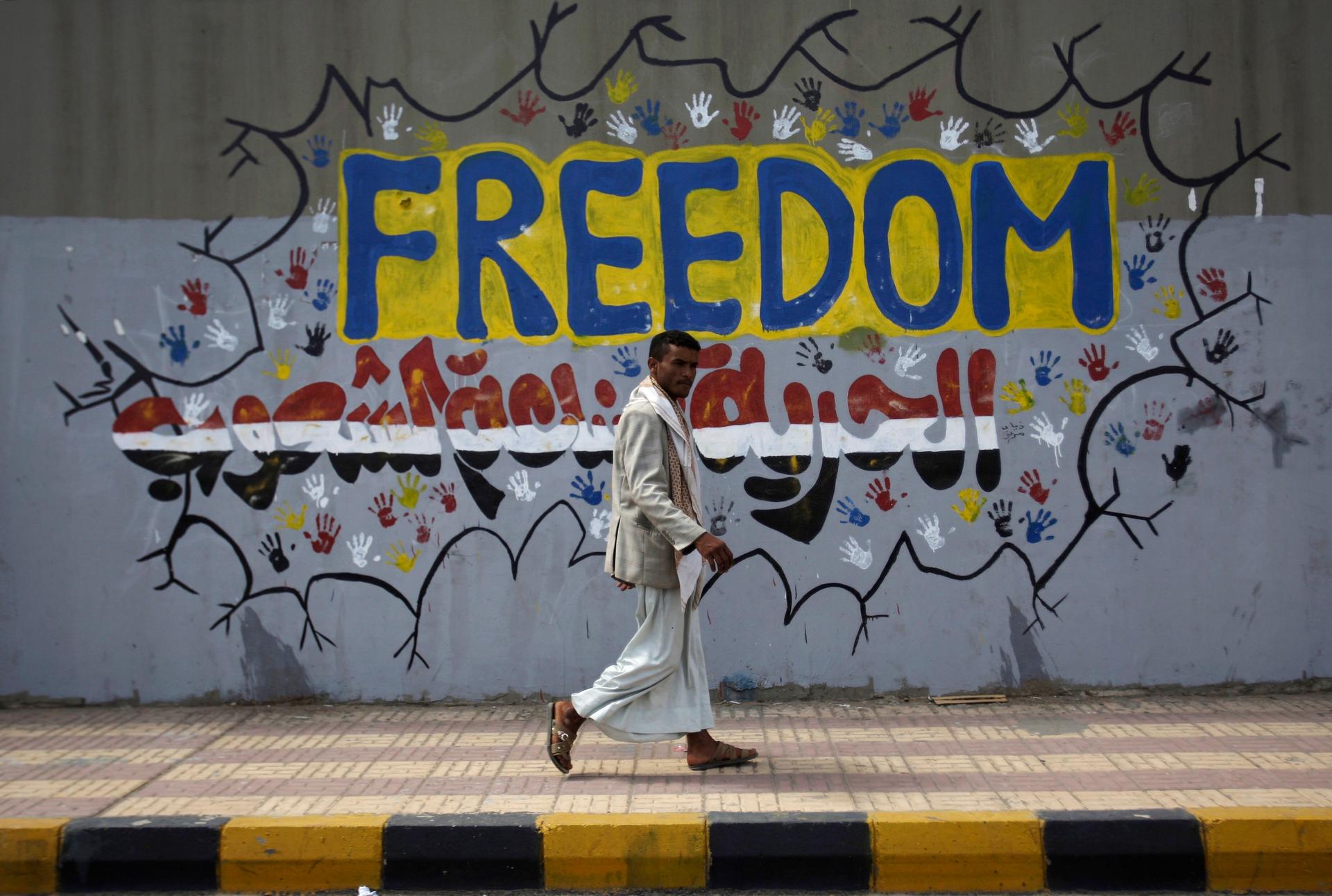 In this Friday, March 2, 2012 file photo, a Yemeni walks past a graffiti that reads 