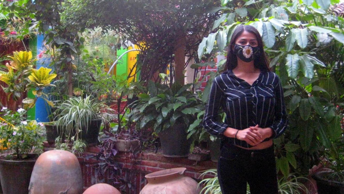 Sandra Martínez stands in a plant-filled patio of the Las Golondrinas Hotel. 