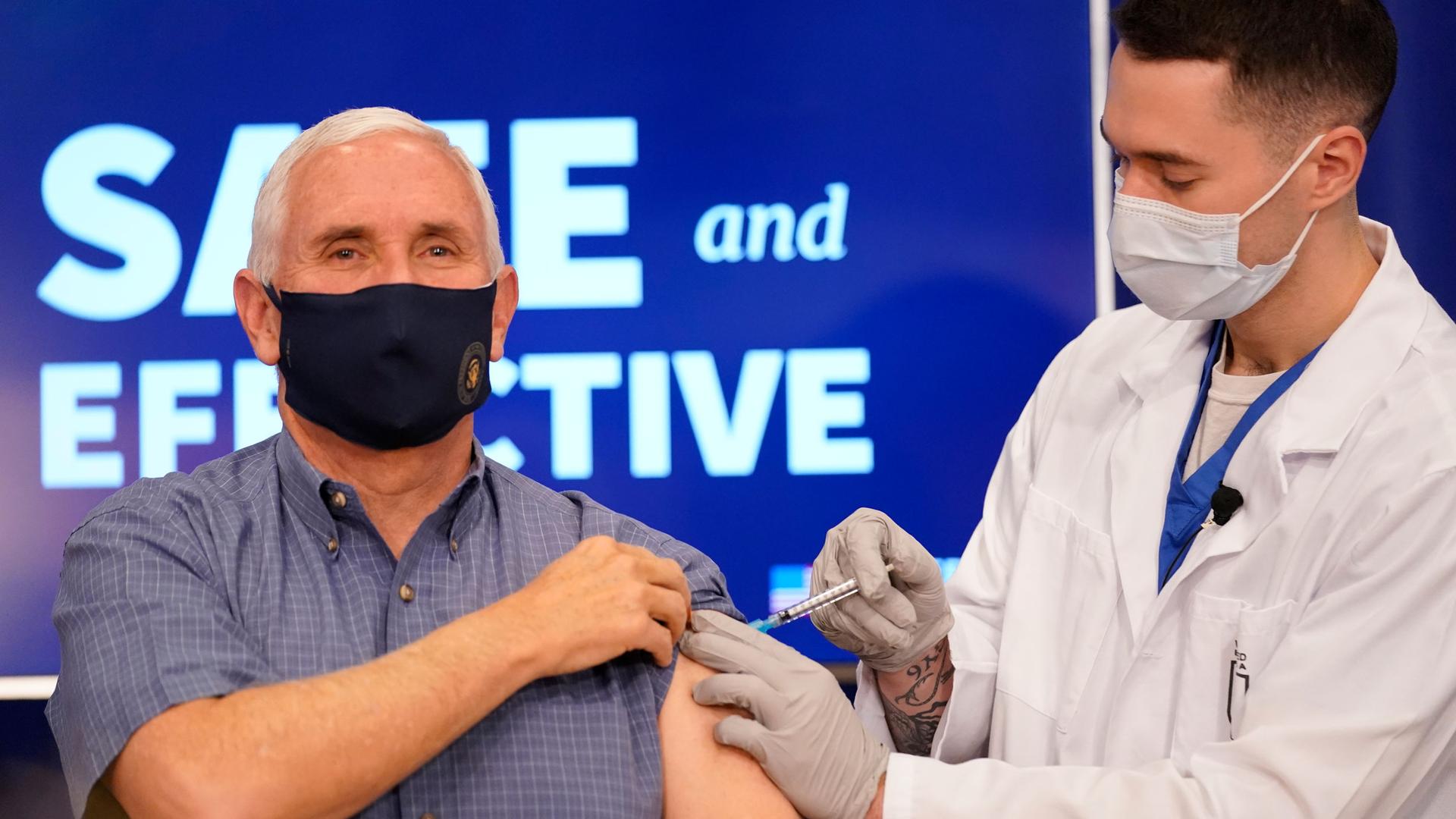 US Vice President Mike Pence is shown holding his sleeve up while a doctor injects the Pfizer-BioNTech COVID-19 vaccine shot in his shoulder.