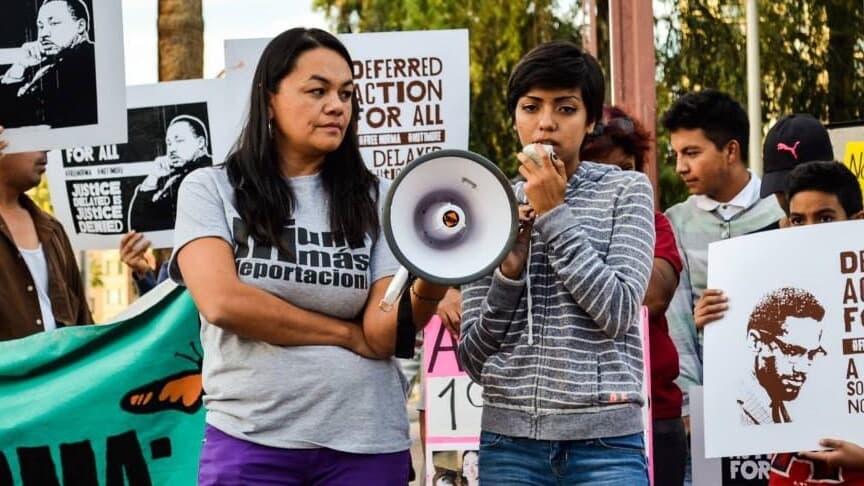 Two people stand at a protest with a loud speaker in their hands.