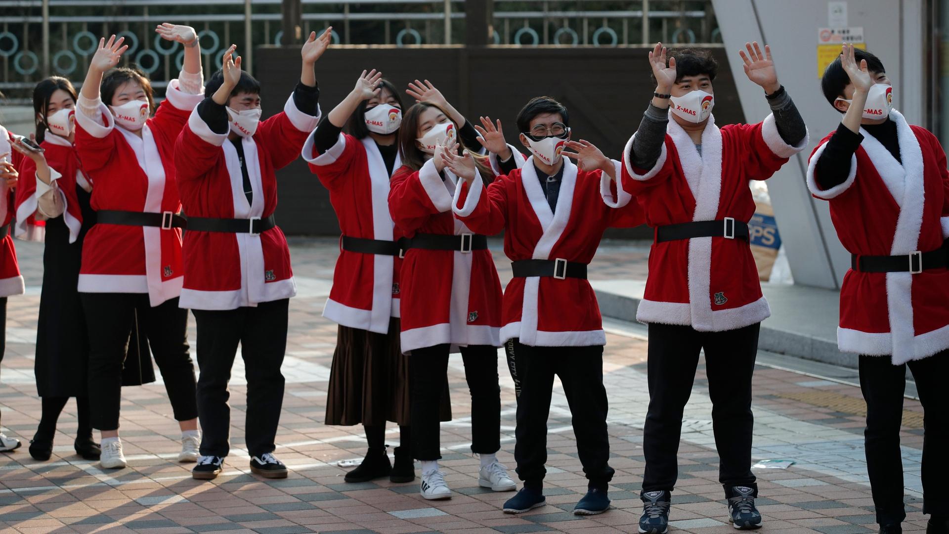 Volunteers wearing face masks wave after they load boxes onto a delivery truck during an event to send Christmas gifts for the underprivileged in Seoul, South Korea, Dec. 22, 2020.