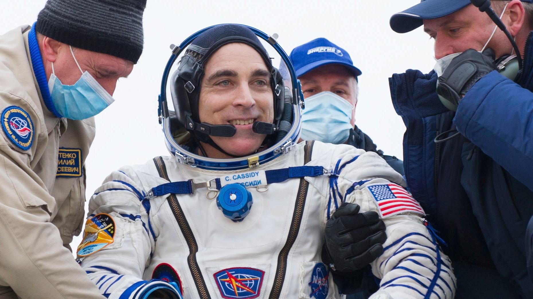 In this handout photo released by Gagarin Cosmonaut Training Centre (GCTC) and the Roscosmos space agency, NASA astronaut Chris Cassidy, center, reacts after landing near the town of Dzhezkazgan, Kazakhstan, Oct. 22, 2020.