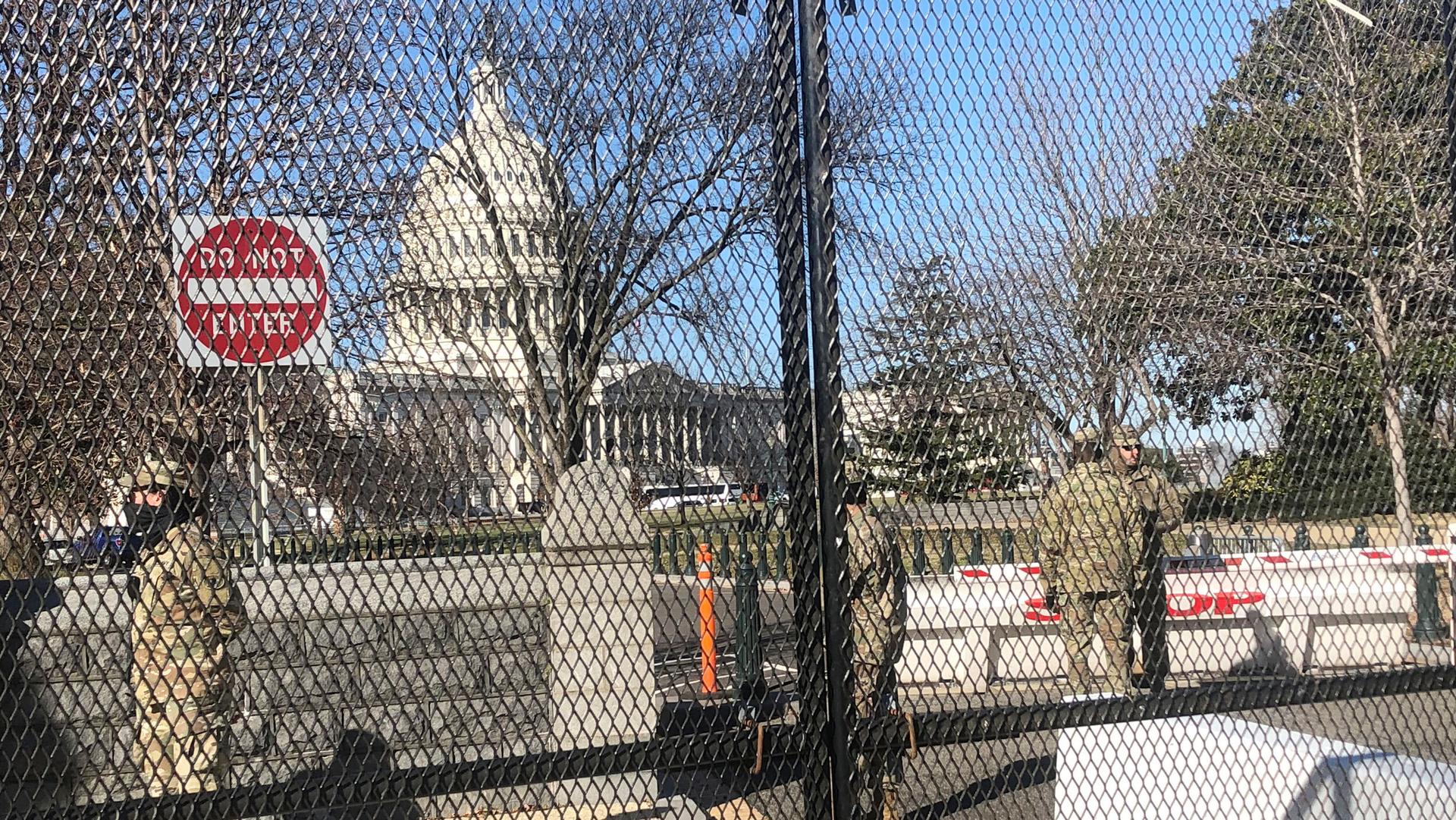 Members of the US National Guard stand inside anti-scaling fencing that surrounds the Capitol in Washington, Jan. 10, 2021.