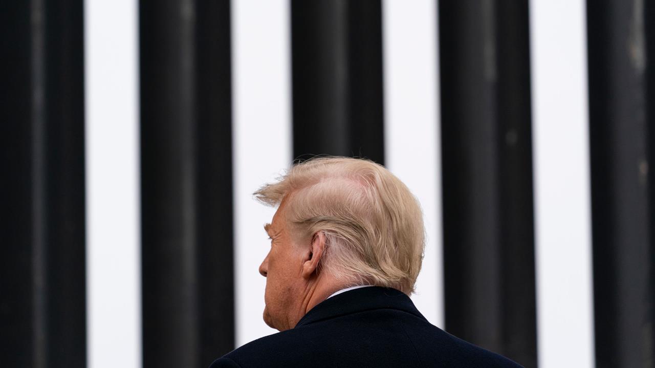 US President Donald Trump faces a black and white striped wall. 