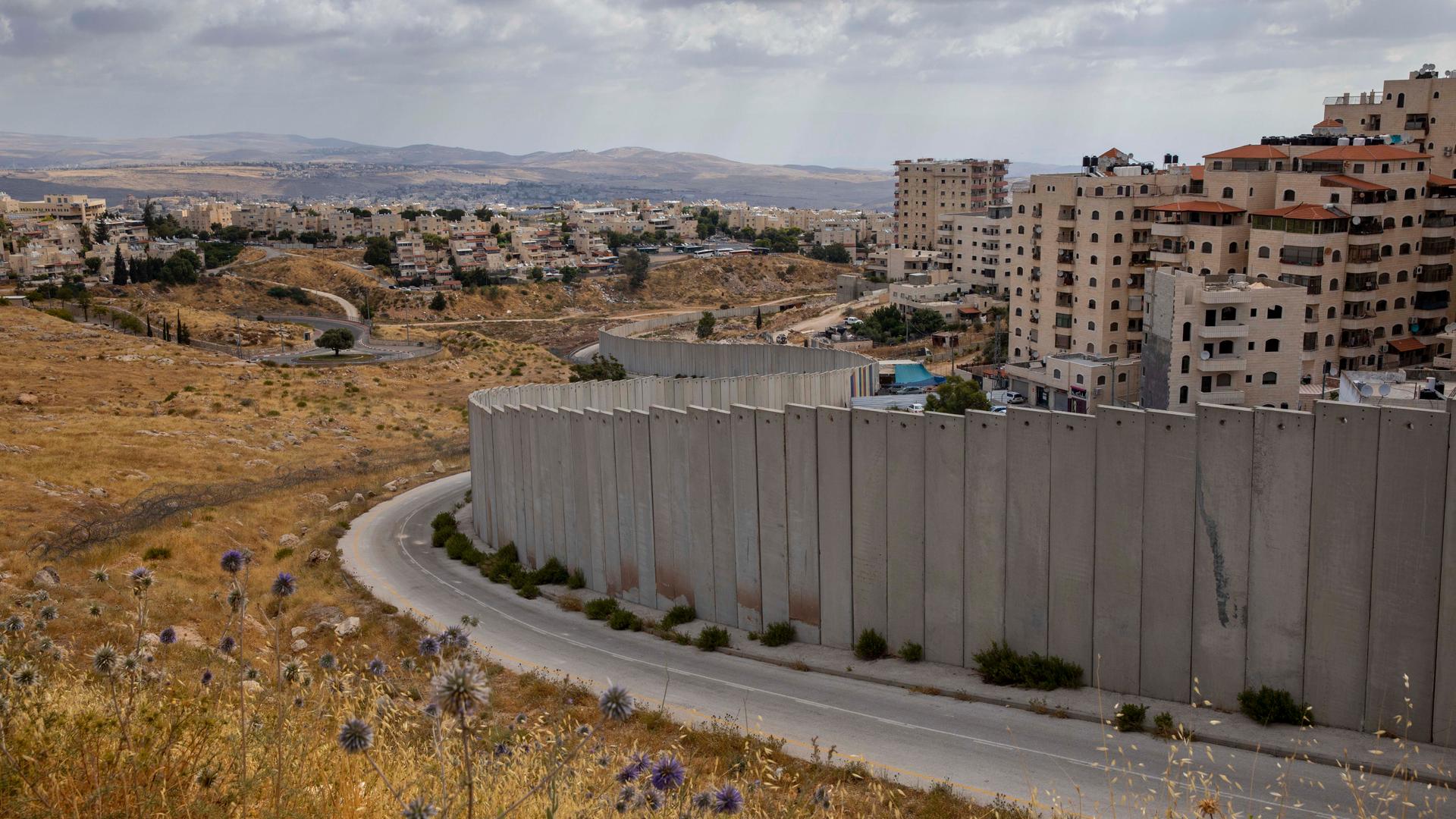 A view of Shuafat refugee camp is seen behind section of Israel's separation barrier in Jerusalem, June 19, 2020. 