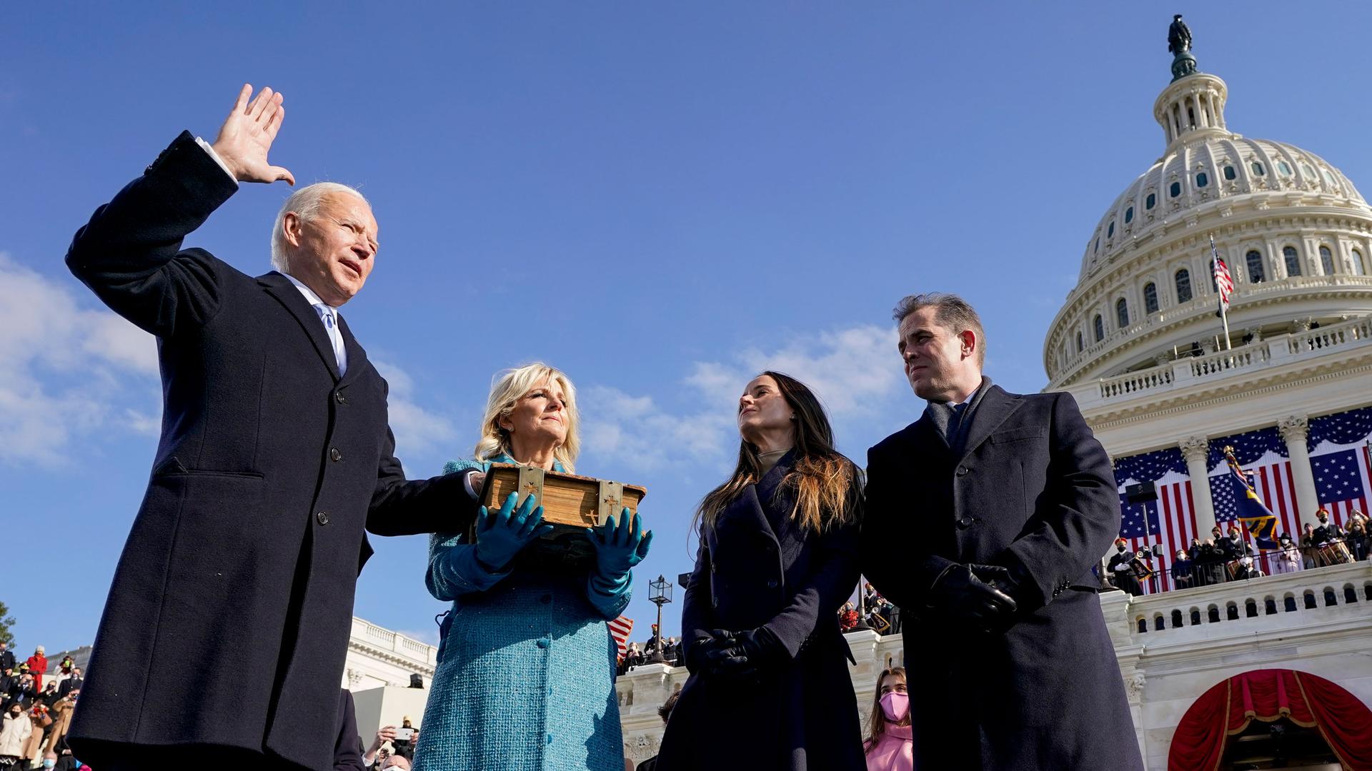 Joe Biden is shown with his right hand in the air and his left hand on a bible as he is sworn in as the 46th president of the United States.