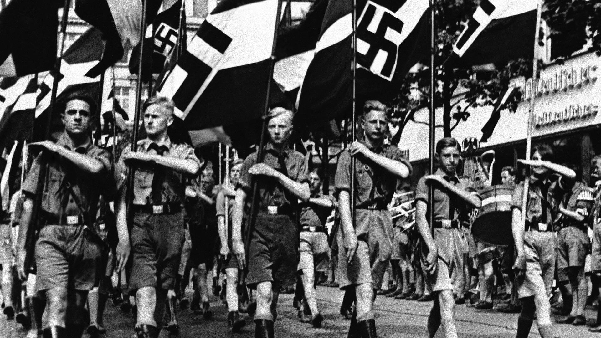 Adolf Hitler's Nazi campaign includes the indoctrination of children in Berlin, Feb. 24, 1936. The boys are trained for future military service and the girls to be obedient hausfraus. Here a group of boys proudly march beneath Nazi standards. 