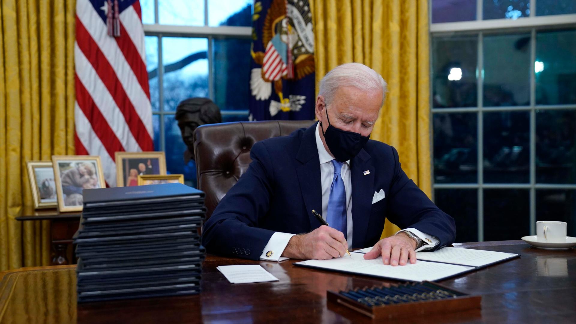 President Joe Biden signs his first executive order in the Oval Office of the White House on Jan. 20, 2021, in Washington, DC.