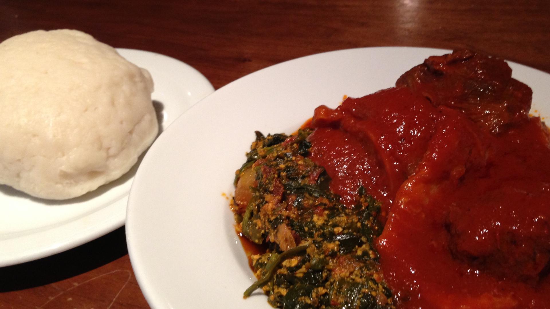 A plate of white fufu with another plate of food with red sauce