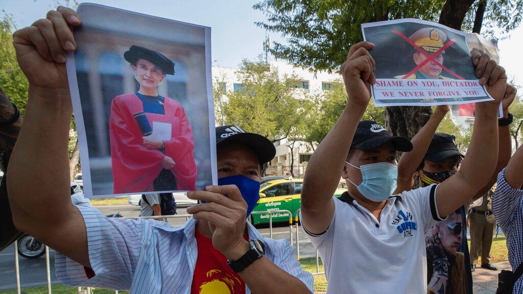 Myanmar nationals living in Thailand hold pictures of Myanmar leader Aung San Suu Kyi and Myanmar military Commander in Chief Senior Gen. Min Aung Hlaing during a protest in front of the United Nations building in Bangkok, Feb. 3, 2021. 