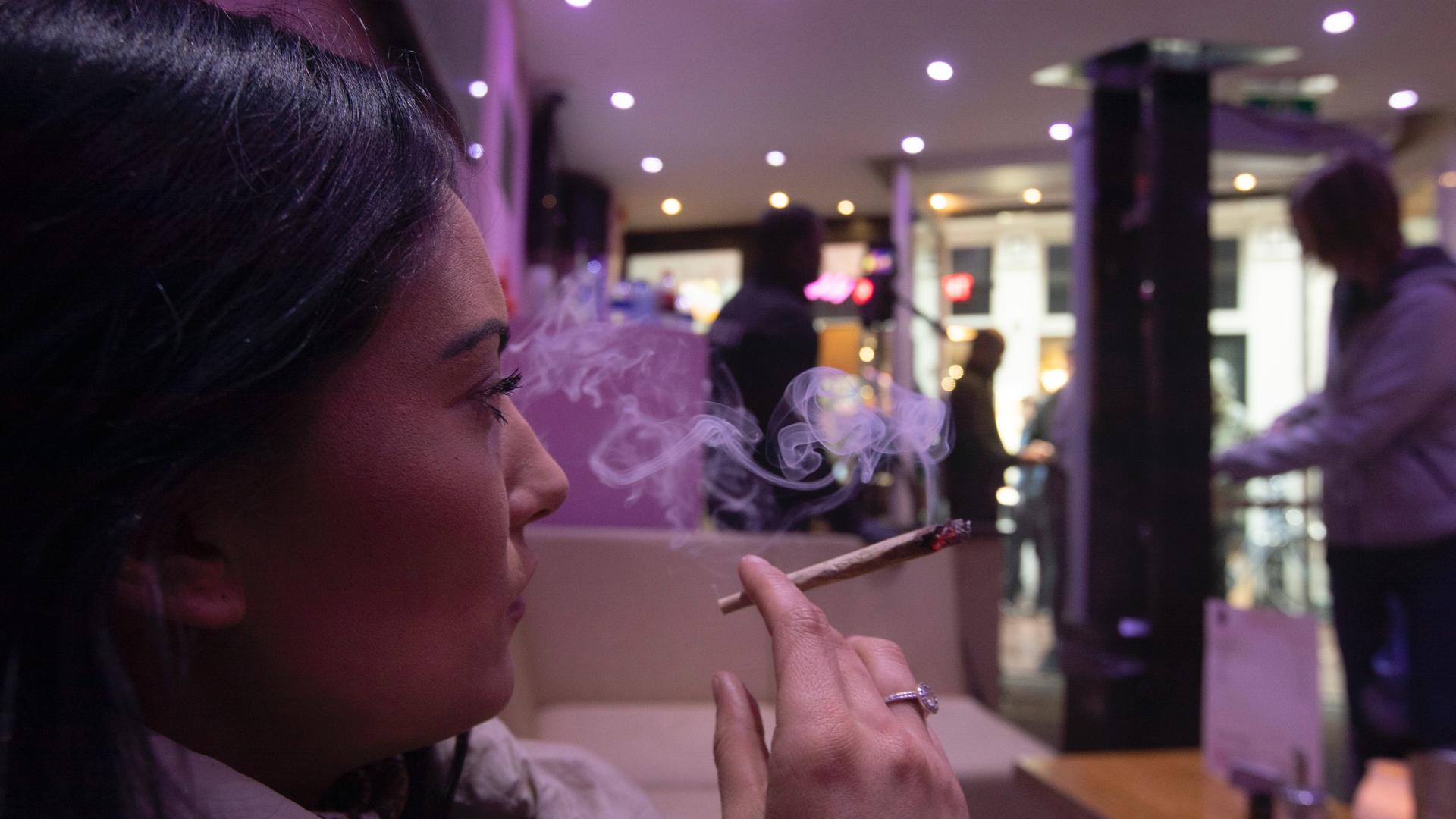 A woman smokes a joint at cannabis coffee shop Prix d'Ami in Amsterdam, Netherlands, March 13, 2020.