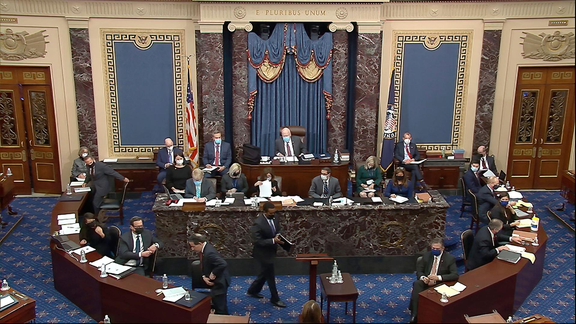 US lawmakers are shown gathering in the Senate with rounded wooden desks encircling a marble dais.