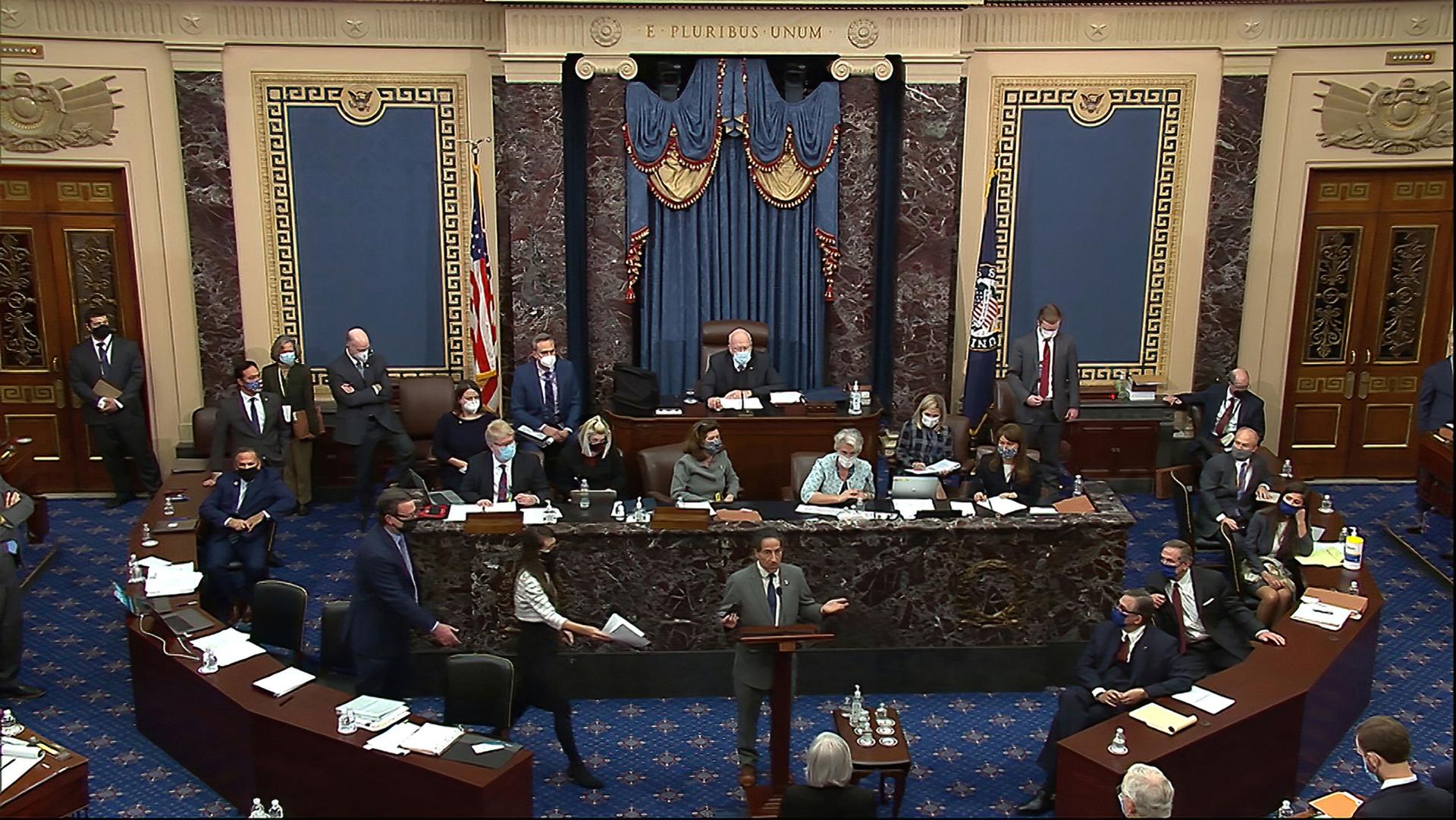 A photo taken from a video above the US Senate chamber showing lawmakers, two rounded wooded tables and the dais.