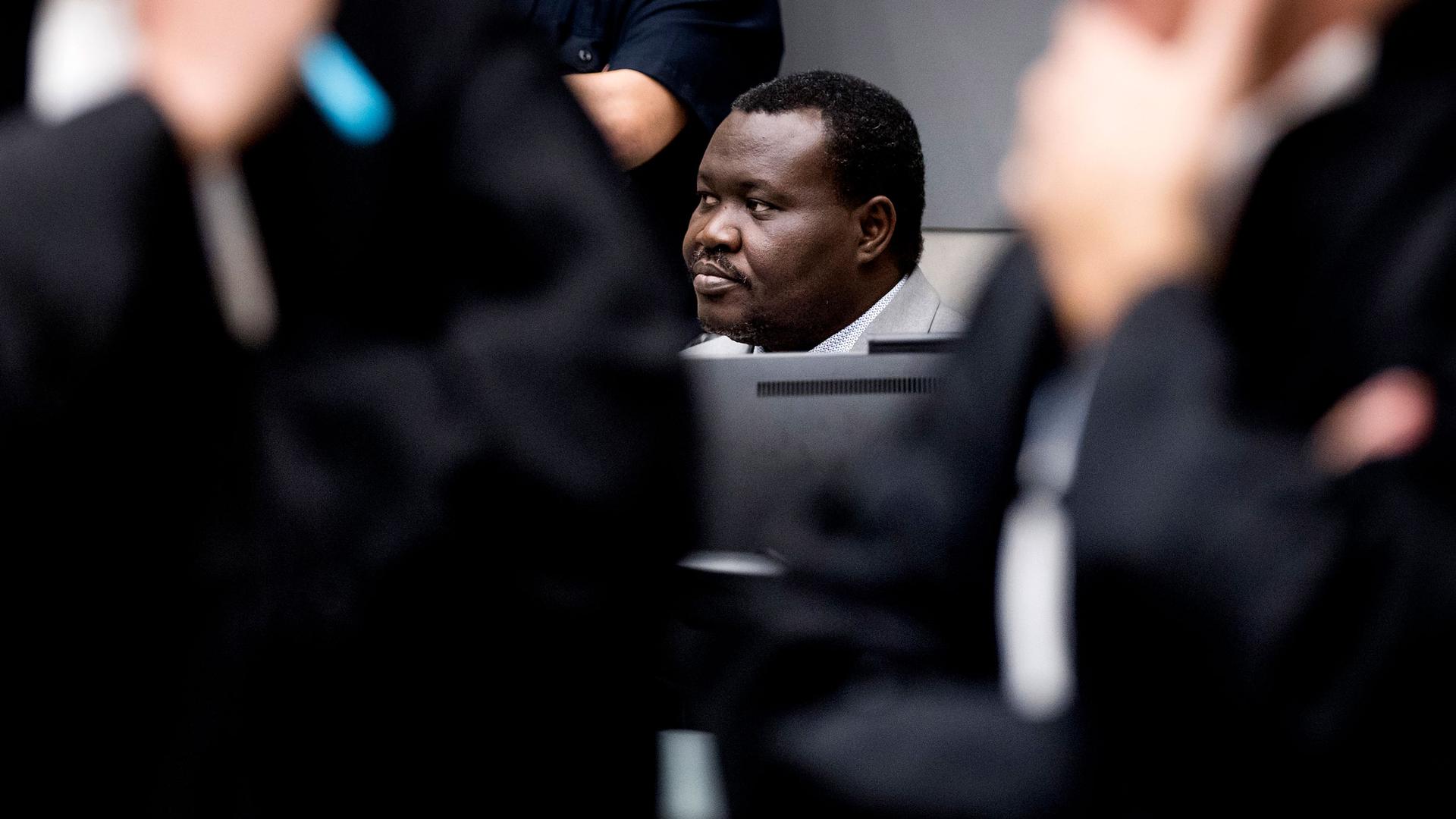 Patrice-Edouard Ngaïssona is seen only from the head up, blocked mostly by ICC judges standing in the nearground.