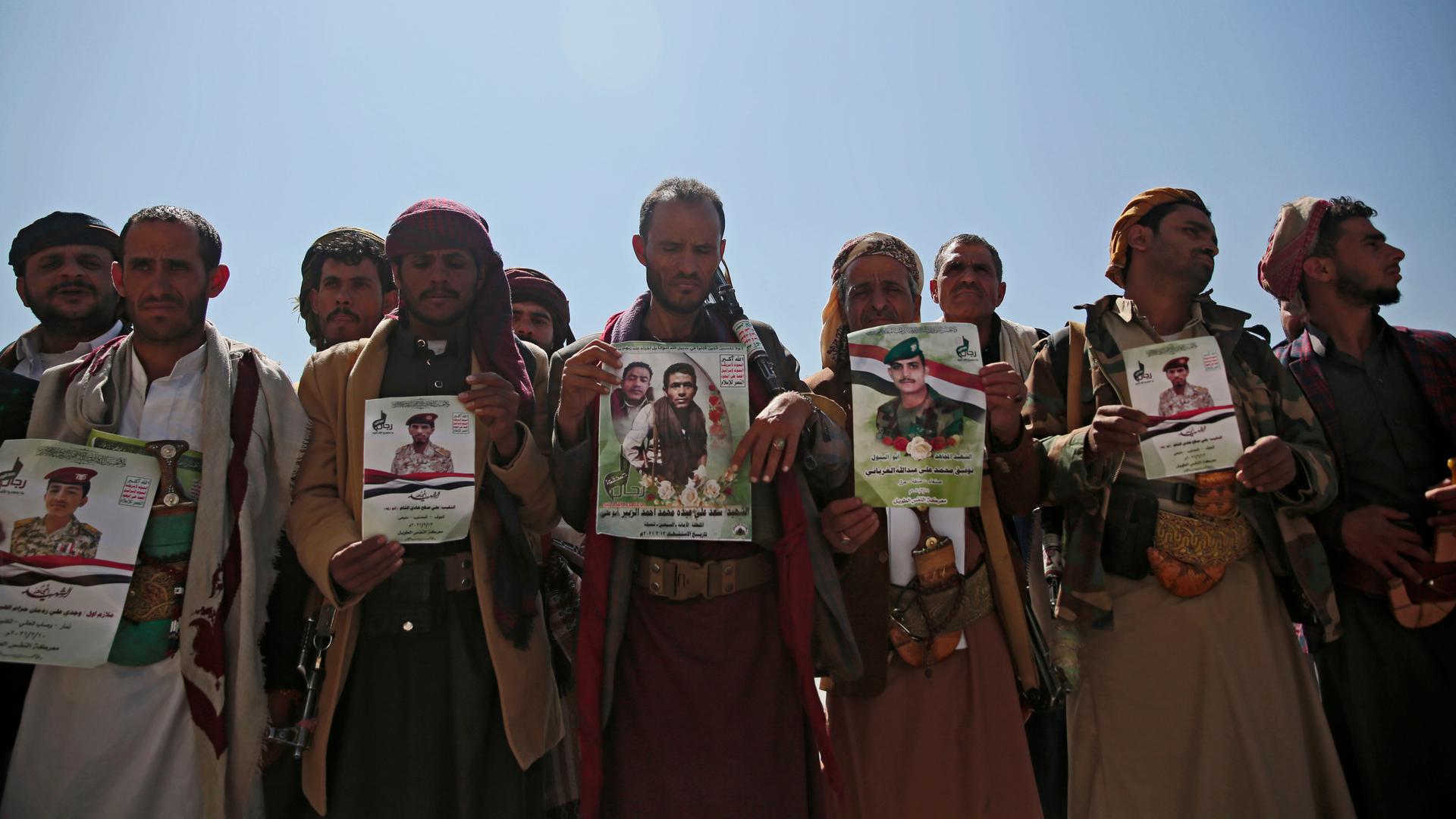 Houthi fighters hold images of relatives killed in violent conflict 