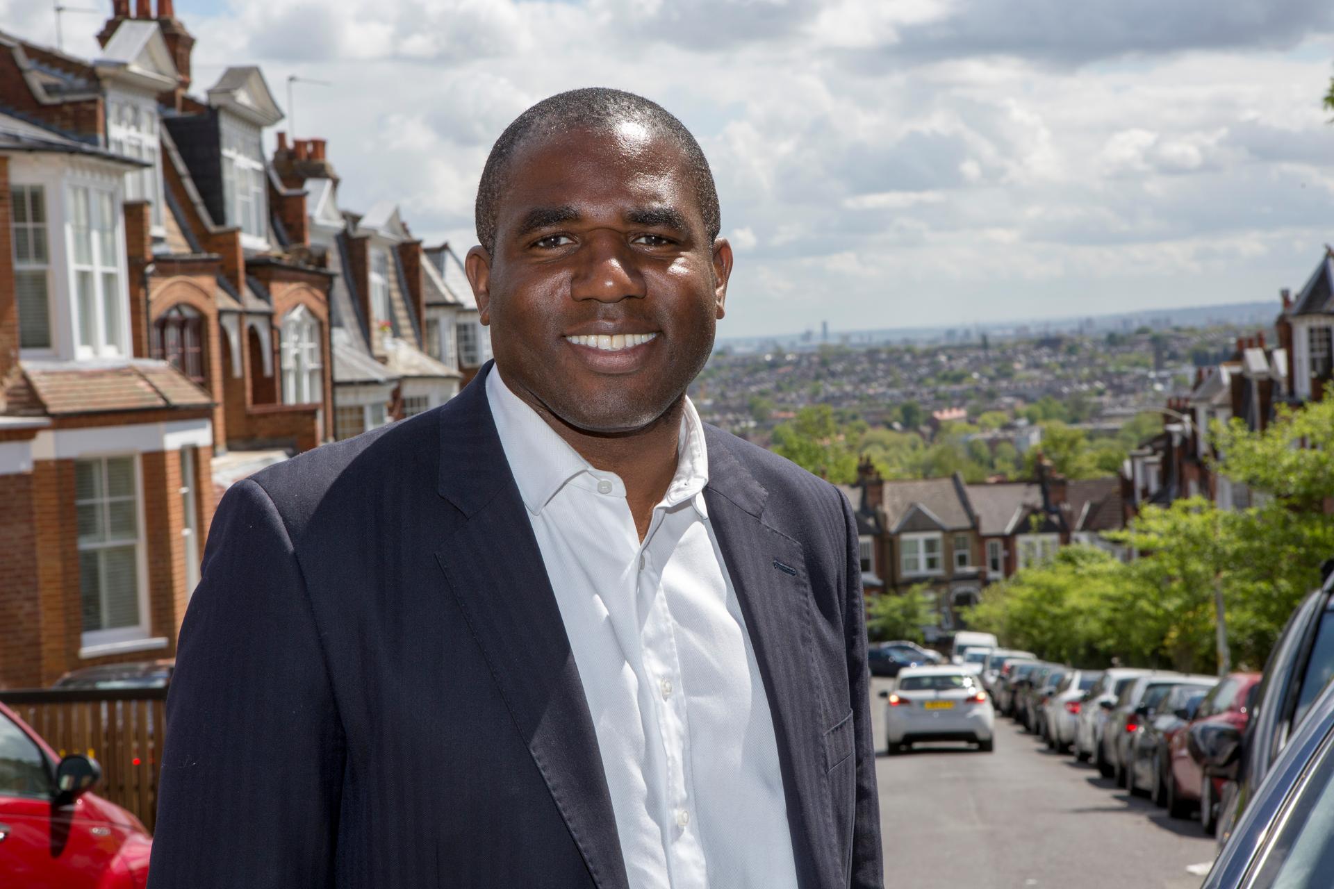 MP David Lammy poses outdoors for a photo wearing a dark suit and white button shirt