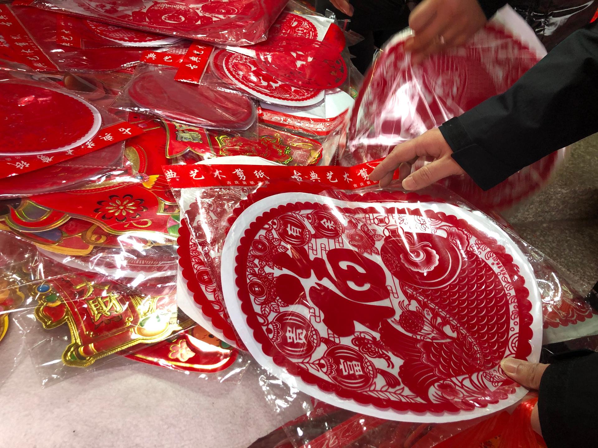 The Chinese government hasn’t actually forbidden holiday travel this year, but they’re strongly discouraging it. So, many people are staying put and finding other ways to celebrate the Chinese New Year — like with red decorations and the like sold in Shan