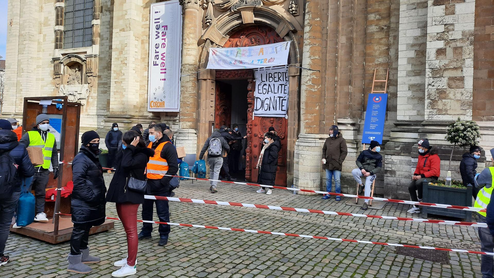 People stand in front of a church door with protest signs on it. 