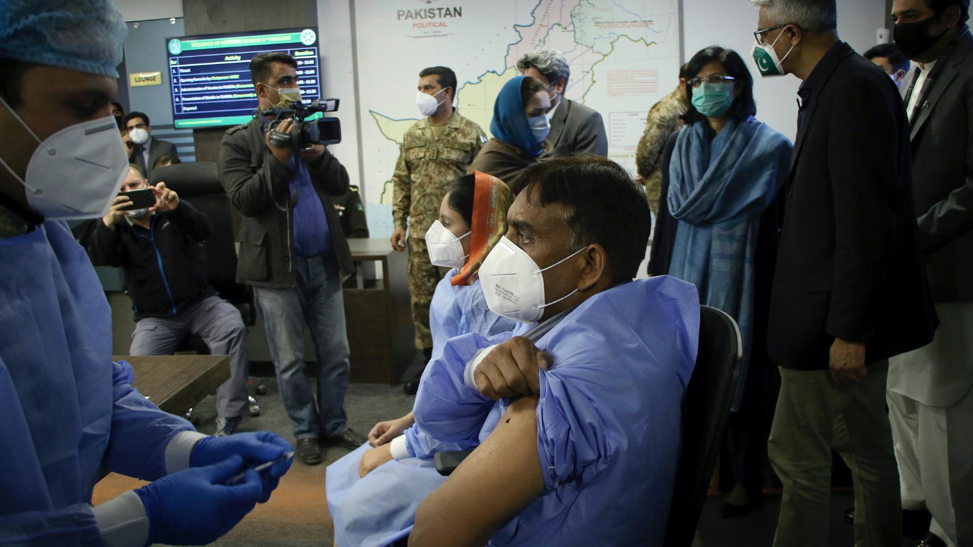 A health worker administers the Chinese Sinopharm COVID-19 vaccine to his colleague while the prime minister's adviser on health issues Faisal Sultan, second right, and other officials watch during a ceremony to start the vaccination campaign in Islamabad