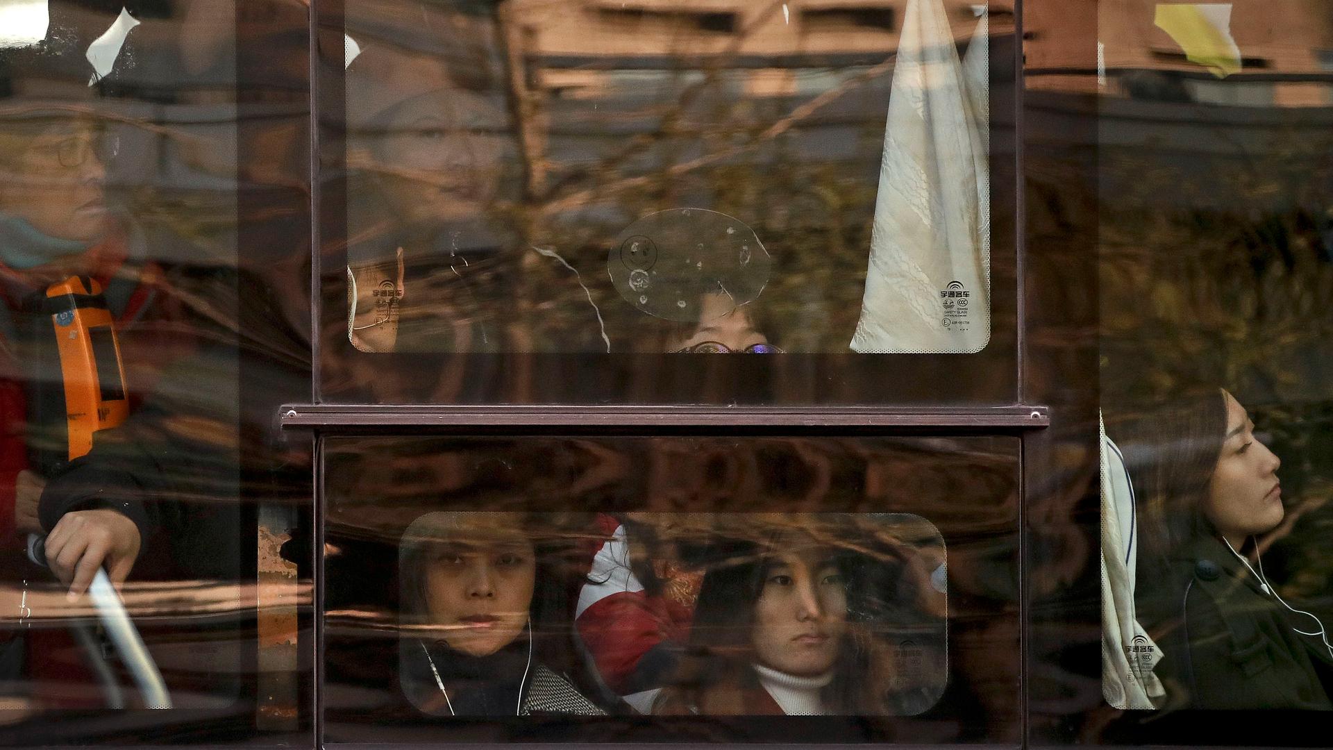 Women look out of a crowded bus traveling from the outskirts of Beijing.