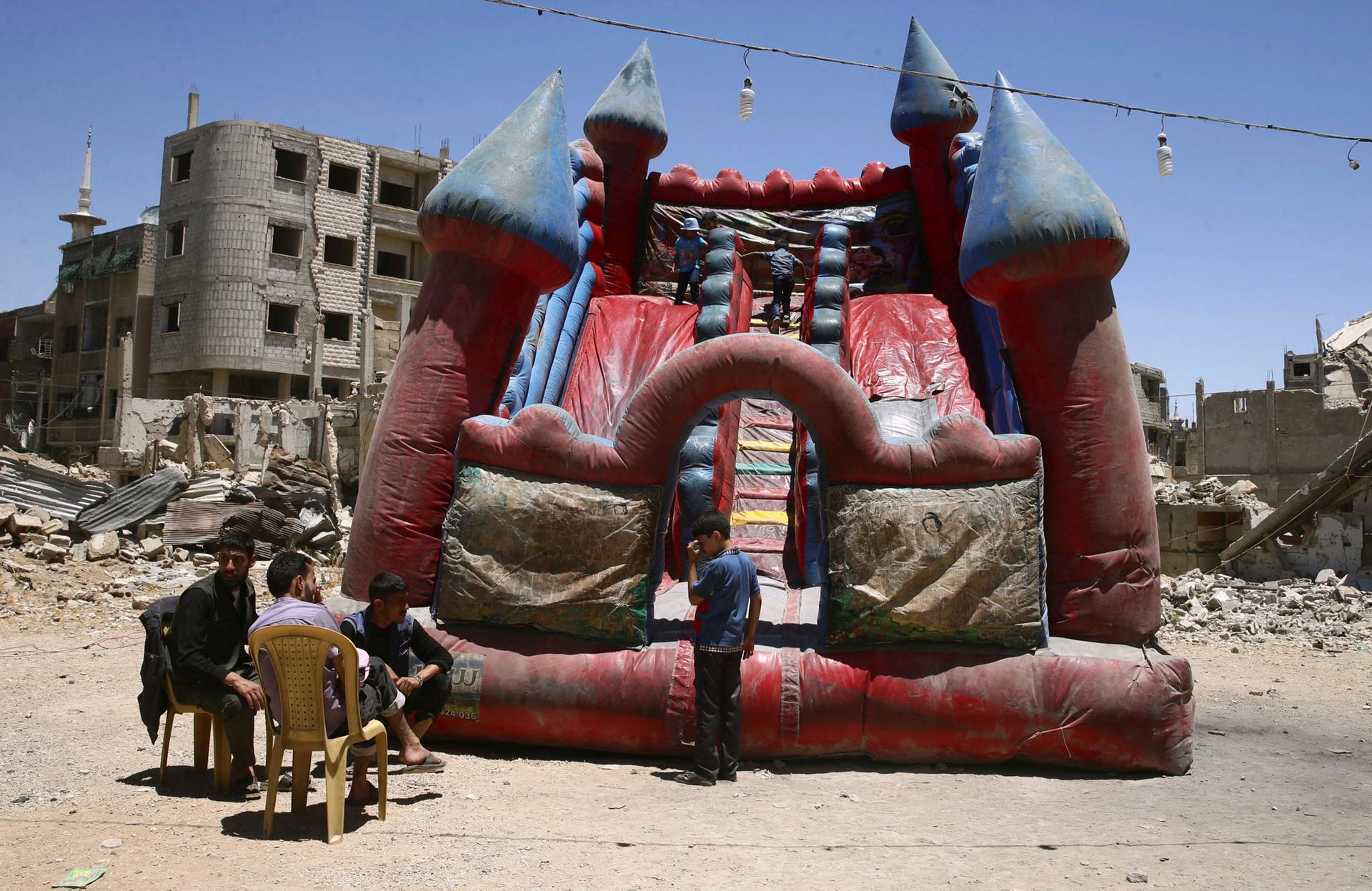 Children play inside an inflatable castle during Eid al-Fitr celebration in the Douma neighborhood of Damascus, Syria, June 26, 2017.