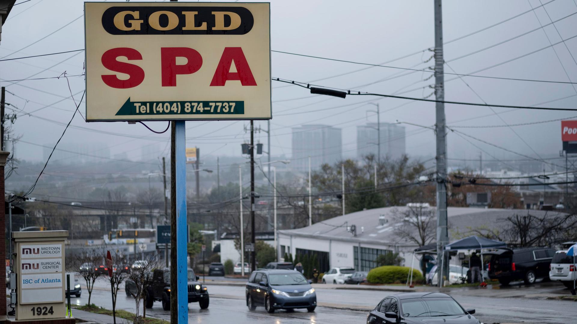 A sign above a roadway is shown for Gold Spa as cars pass by on a rainy afternoon.