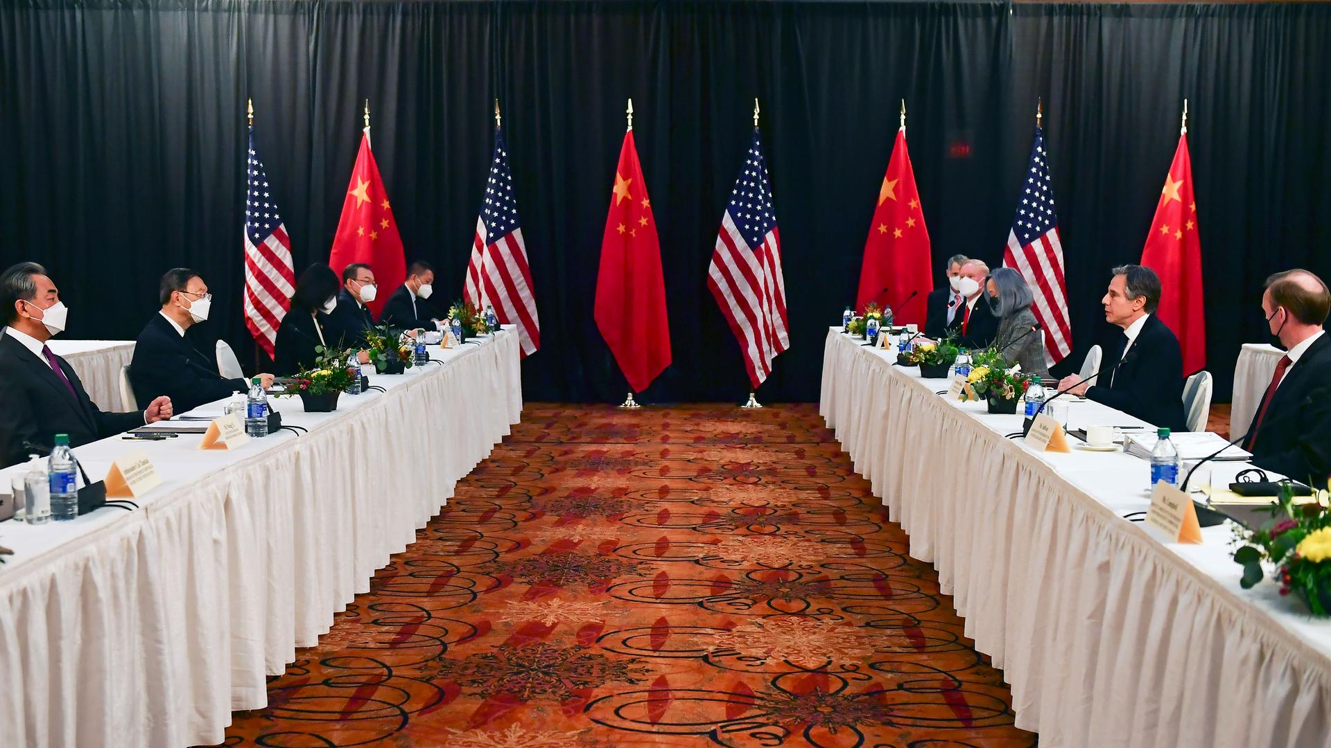 Two long rows of tables are shown with white table cloths and officials on either side with US and Chinese flags in the distance.