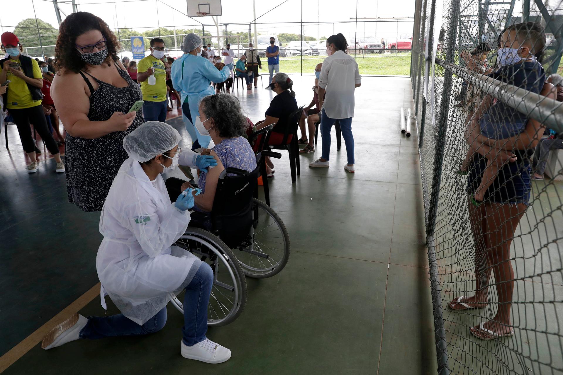 A health worker inoculates a woman at a COVID-19 vaccination point for priority elderly persons in the Ceilandia neighborhood, on the outskirts of Brasilia, Brazil, March 22, 2021.