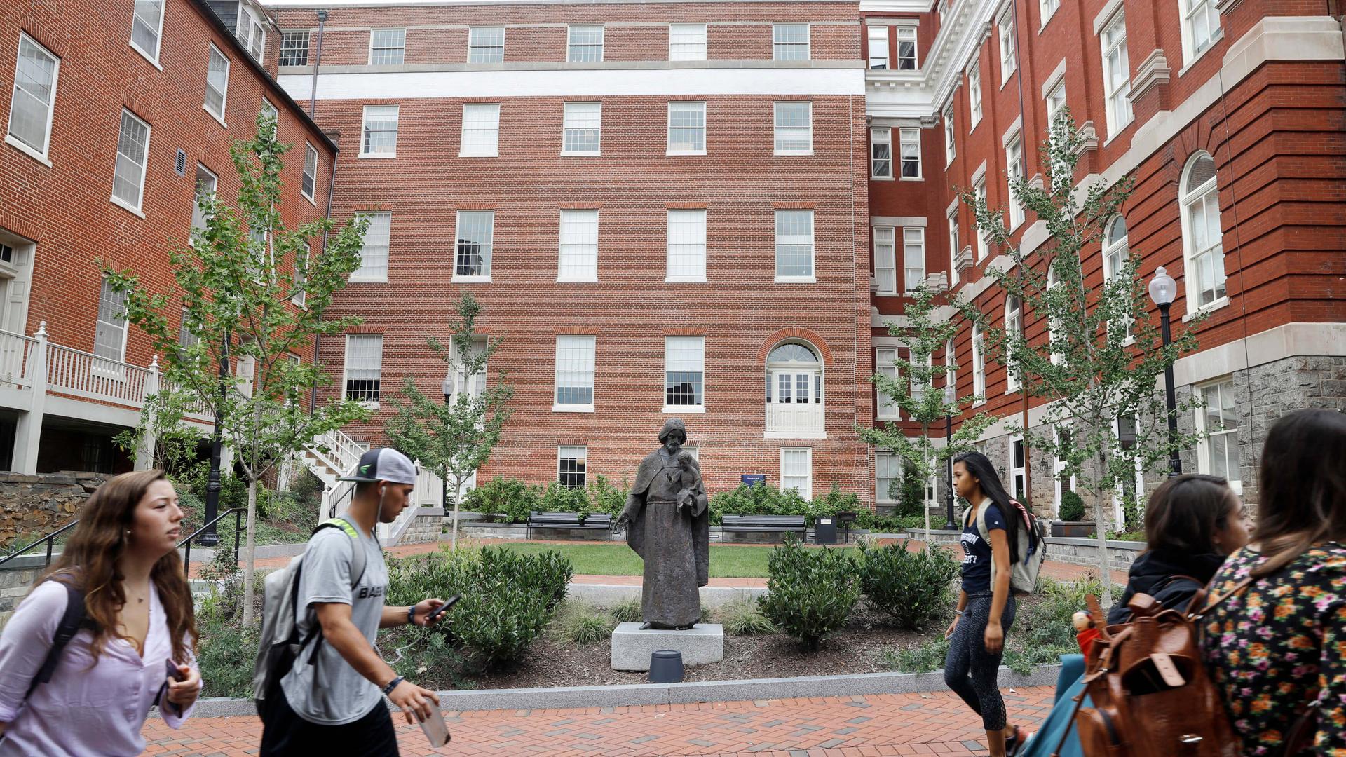 In this Sept. 1, 2016 file photo, a Jesuit statue is seen in front of Freedom Hall, formerly named Mulledy Hall, on the Georgetown University campus in Washington. 