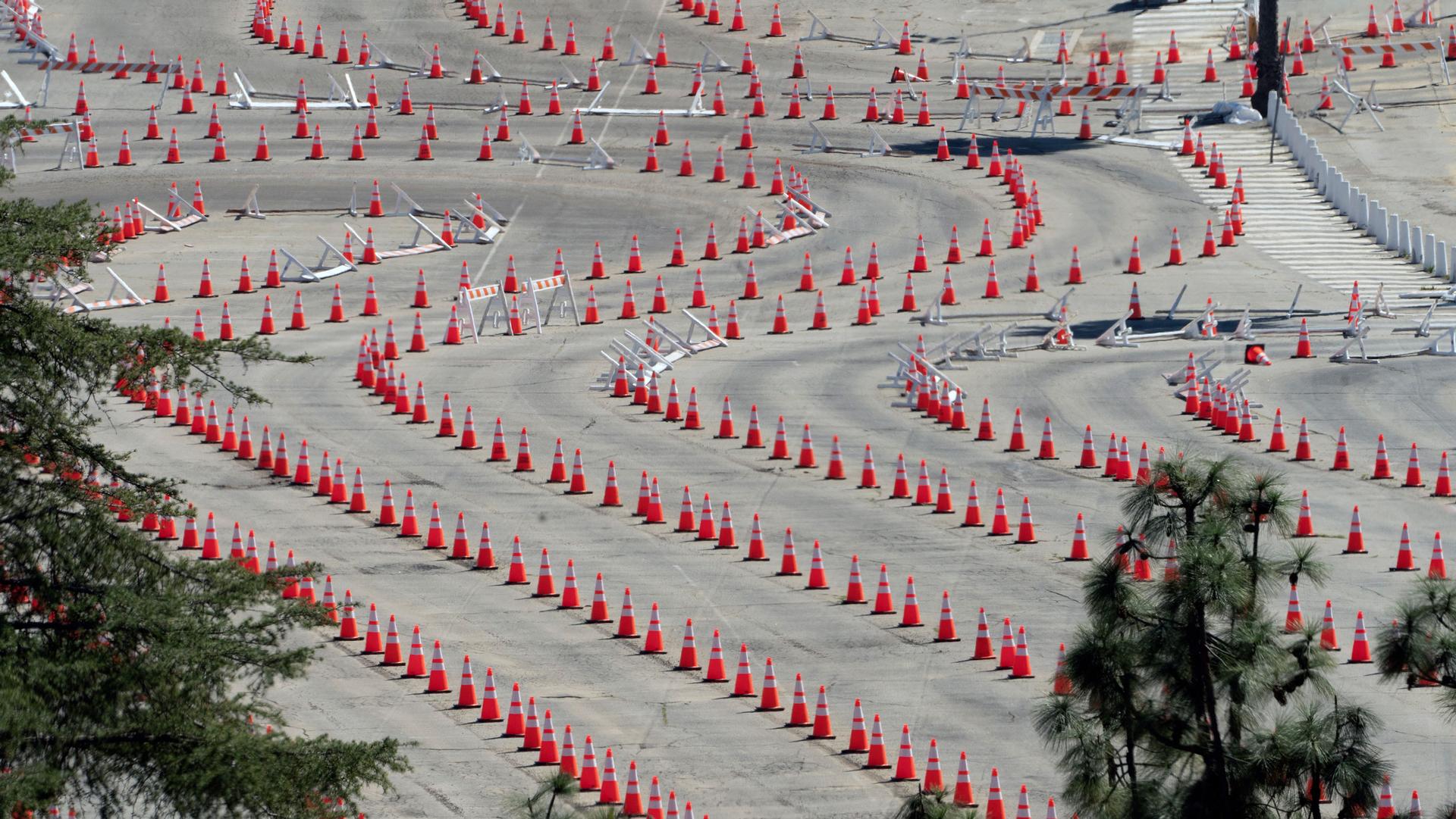 Several long lines of traffic cones are shown winding around an empty parking lot.