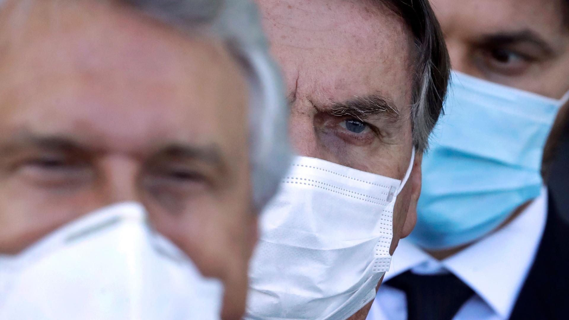 Brazilian President Jair Bolsonaro is pictured in a close up photograph showing only his face covered by a medical face mask.