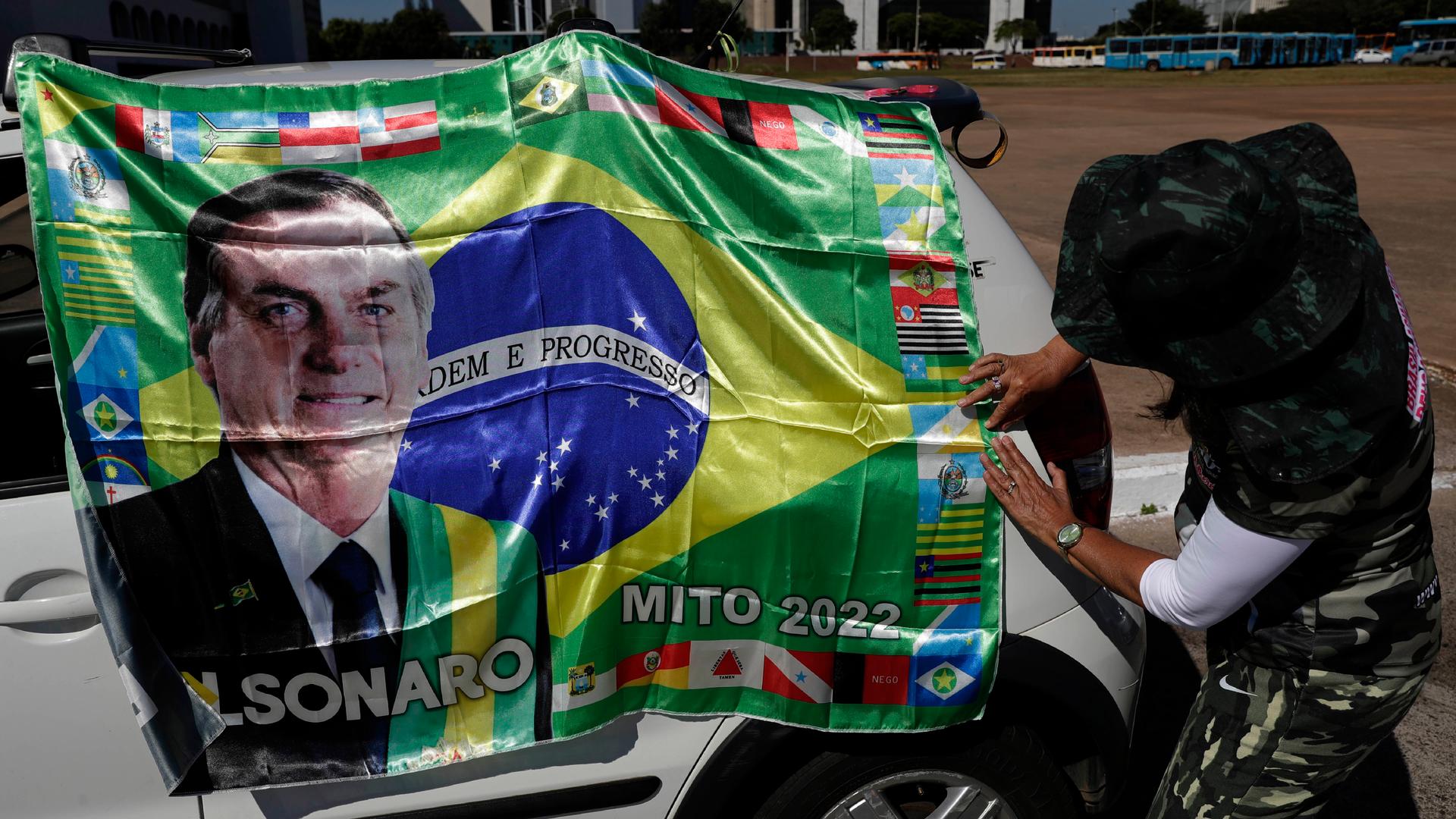 A supporter of Brazilian President Jair Bolsonaro places his image on a car.