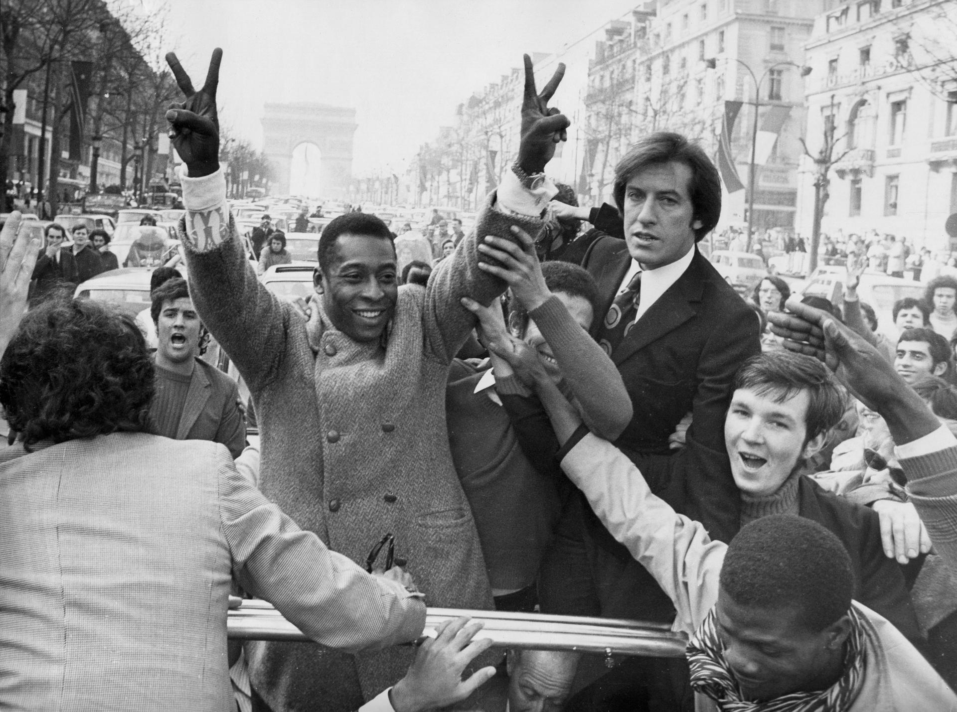 Pele standing and flashing a victory sign, surrounded by happy French people, in Paris 