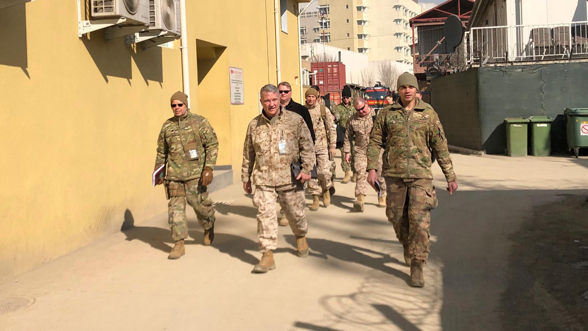 Group of US generals in army fatigues walk through the street in Afghanistan.