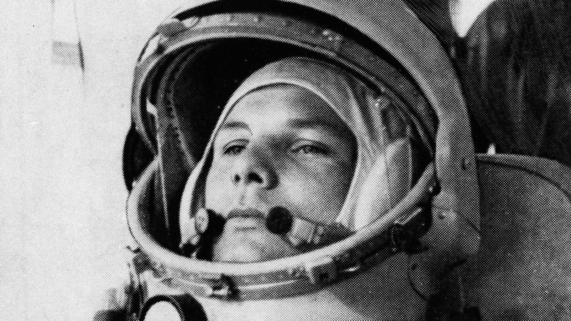 Soviet cosmonaut Major Yuri Gagarin is shown in a black and white portrait photograph wearing a space helmet with the visor open.