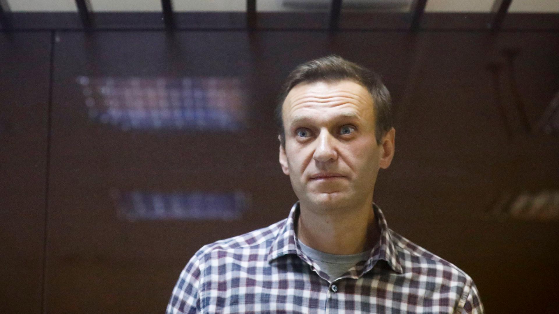 Alexei Navalny wears a plaid shirt and looks a bit startled with his eyes widened at the camera. 