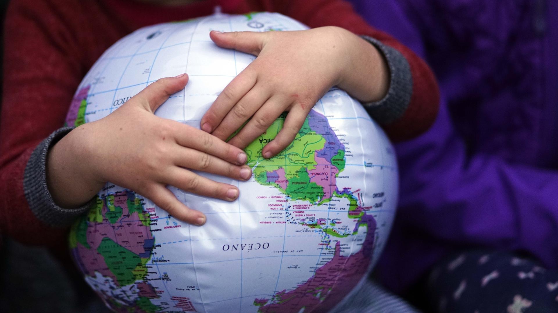 Child holds onto an inflatable globe