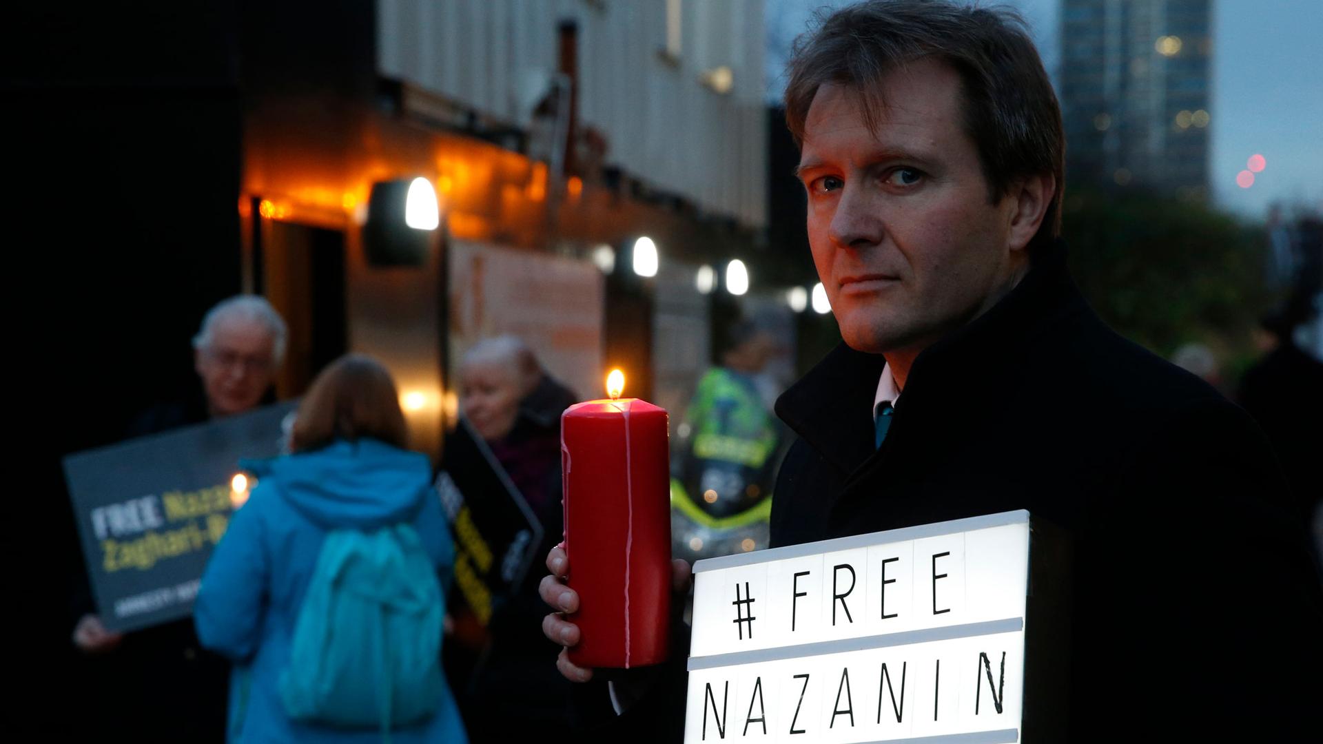 Richard Ratcliffe is shown holding a red candle and a sign that says #Free Nazanin on it.