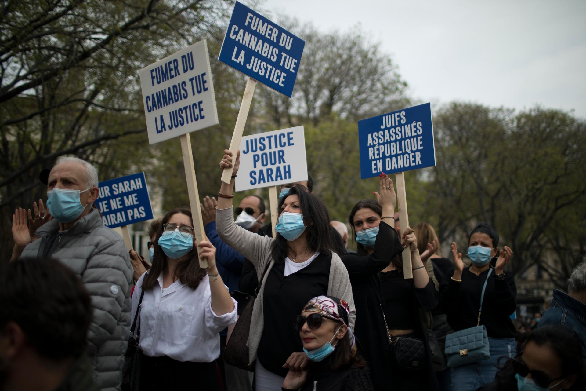 Protesters hold blue and white signs in French that read 