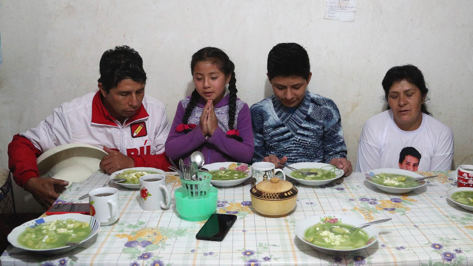 Free Peru party presidential candidate Pedro Castillo, from left, daughter Alondra, son Arnold and wife Lilia Paredes, pray before eating breakfast, in their home in Chugur, Peru, April 16, 2021. Castillo, a rural teacher, who has proposed rewriting Peru'