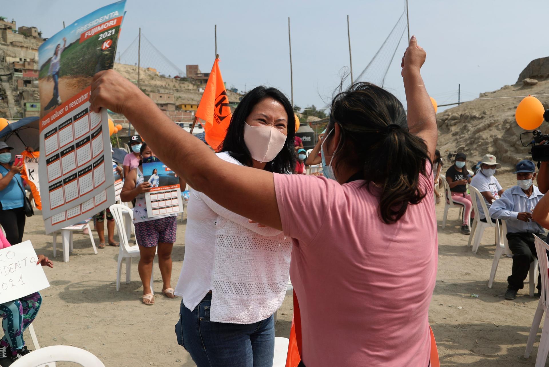 Wearing a mask to curb the spread of the new coronavirus, presidential candidate and daughter of imprisoned ex-President Alberto Fujimori, Keiko Fujimori, of the Popular Force party, greets a supporter as she campaigns in San Juan de Lurigancho on the out