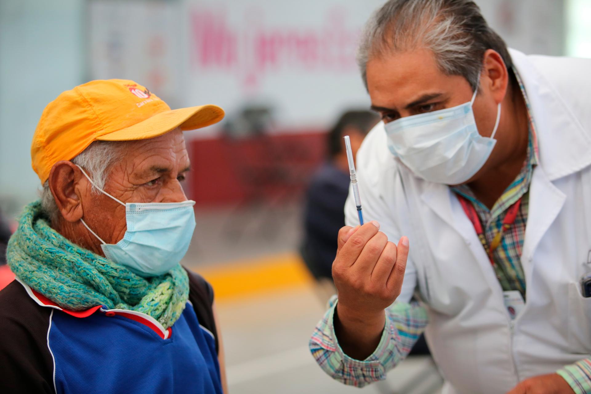 A nurse shows an elderly man a syringe prepared with a dose of the Sinovac COVID-19 vaccine, before he is inoculated at the Americas Cultural Center in Ecatepec, Mexico, April 3, 2021.