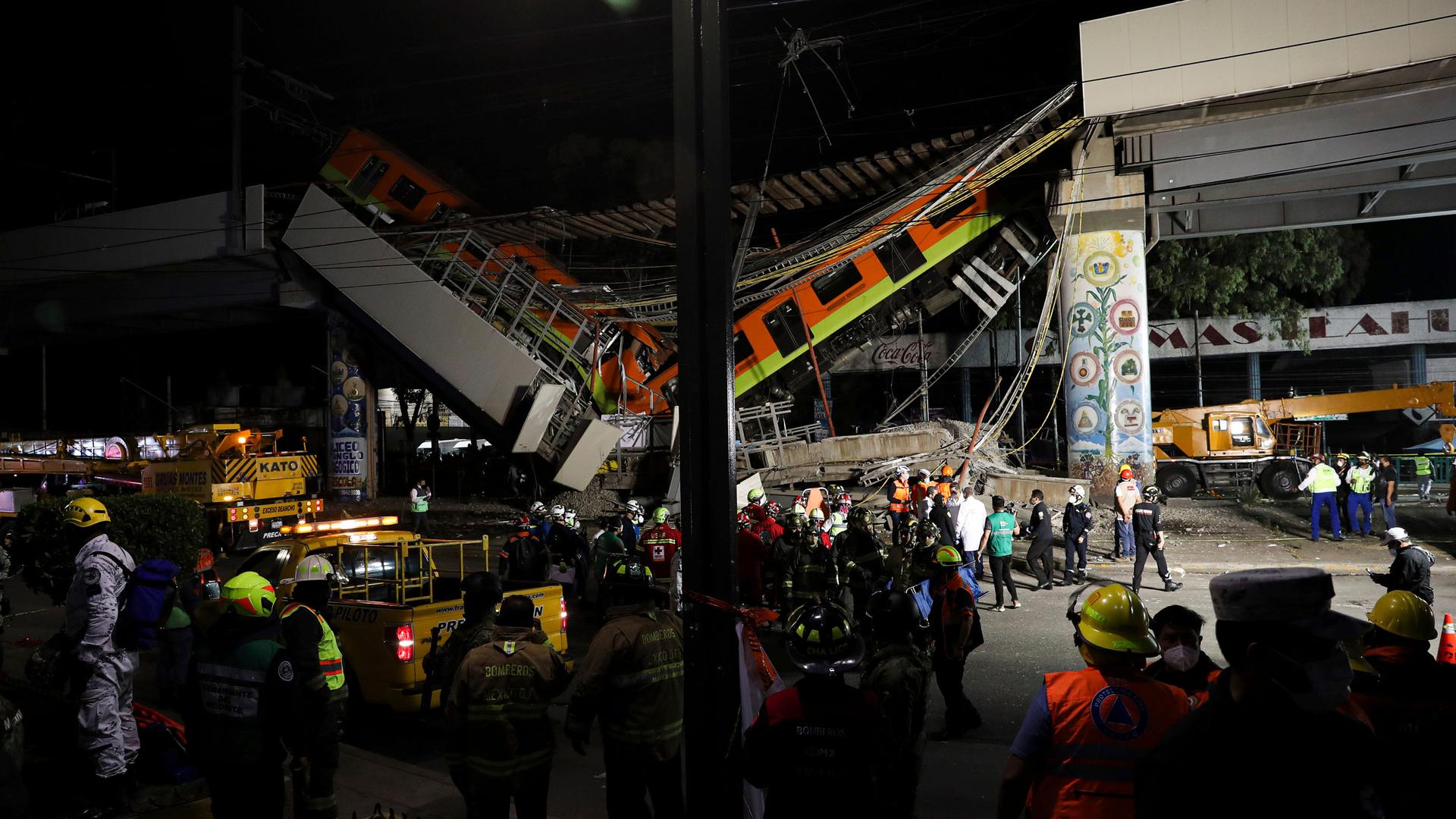 Two subway cars are show fallen from an elevated train track with rescue workers all around.