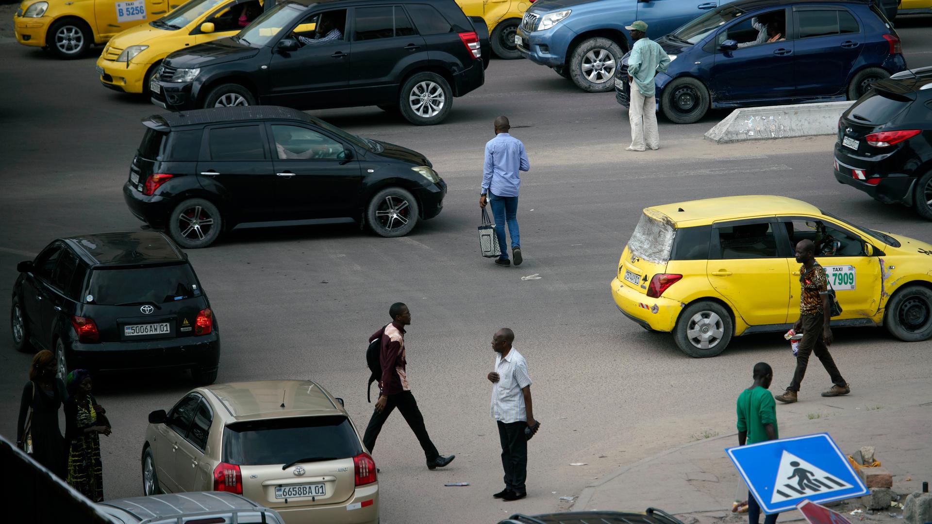 Pedestrians cross a busy street in Kinshasa. 