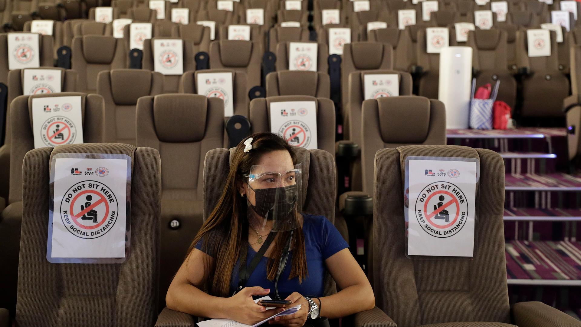 A sole woman waits in an empty movie theater-turned vaccination hub for her vaccine at a mall