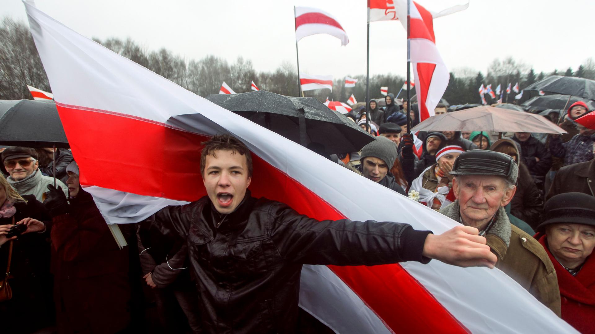 Man in black jacket holding red and white flag