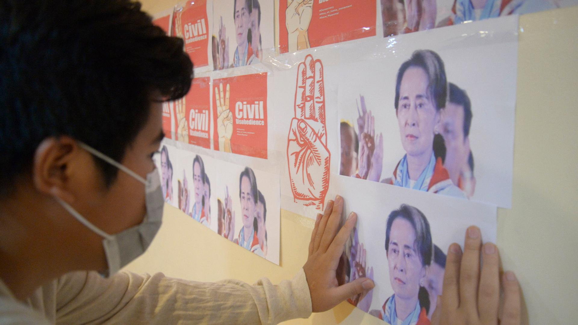 An anti-coup protester looks at the images of ousted Myanmar leader Aung San Suu Kyi during a protest against the military coup in Yangon, Myanmar, on April 26, 2021.