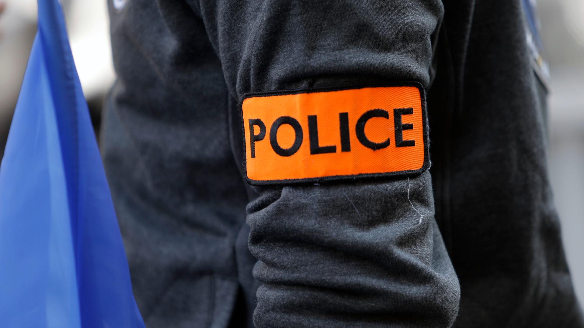 An arm with an orange band with black letters spelling out "Police" 
