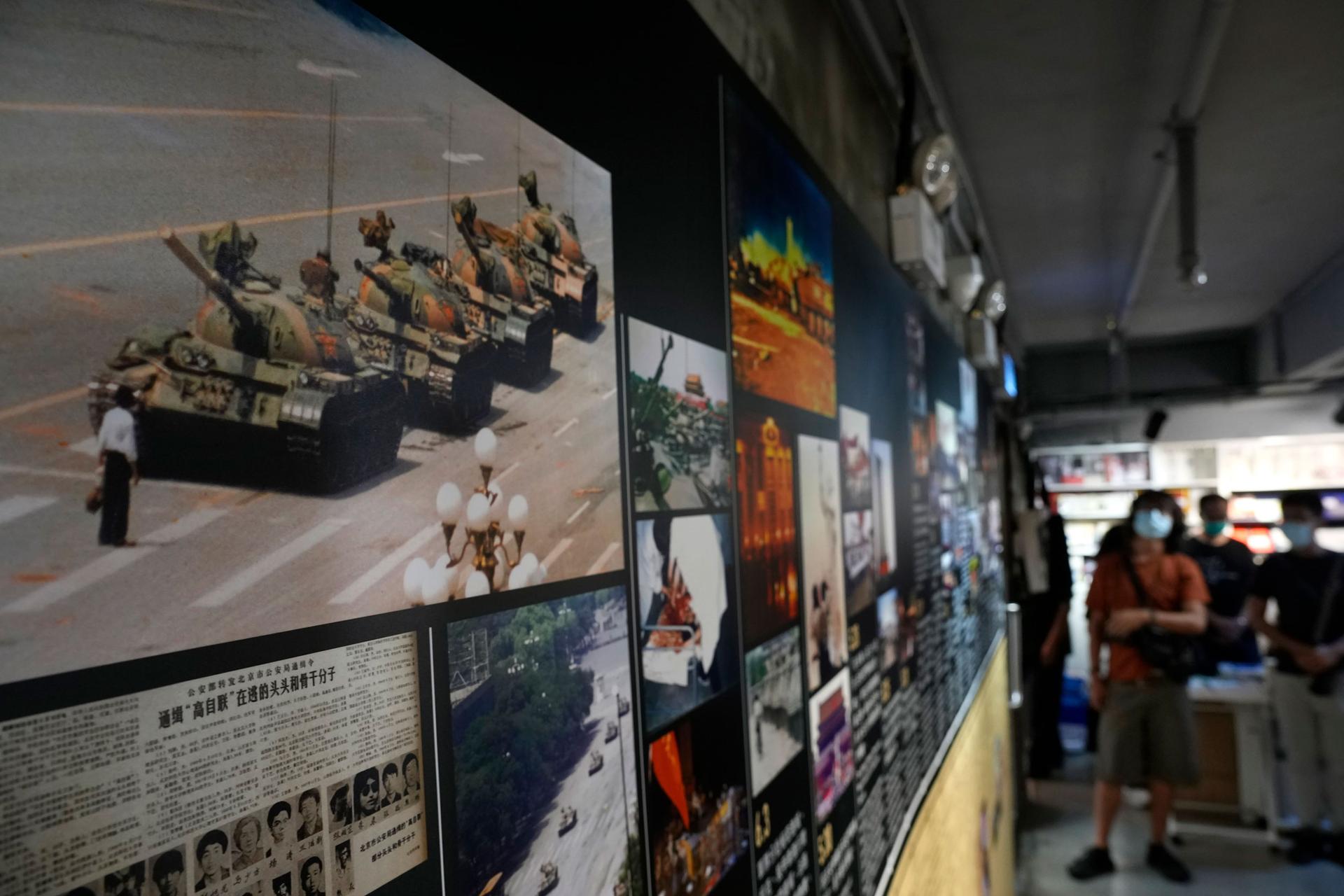 A photograph of a man blocking a line of four tanks in a street is shown hanging with other photographs and newspaper clippings.