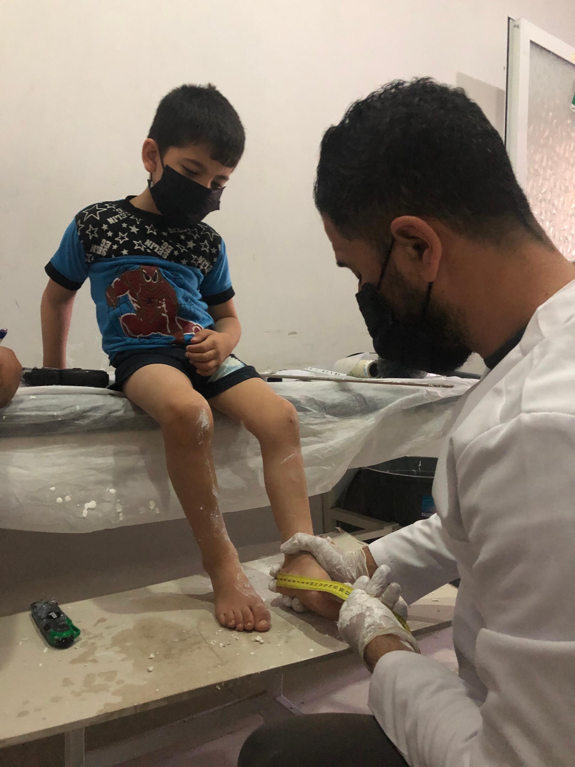 Five-year-old Jad al-Aweis suffers from cerebral palsy due to lack of oxygen at birth. Here, a specialist at a prosthetic limbs center in Turkey takes measurements of his legs so he can make braces that will help Jad walk.